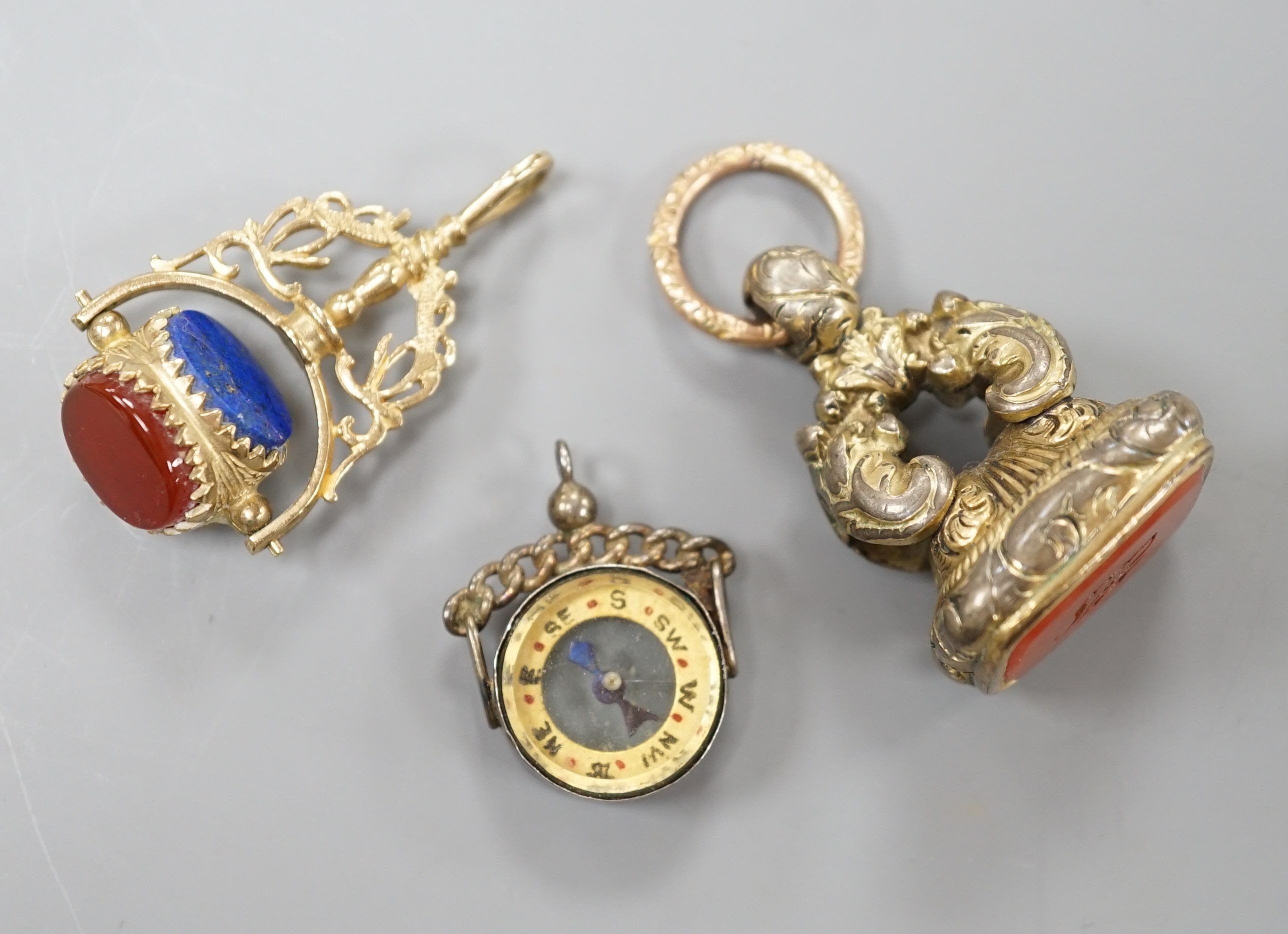 A modern 9ct gold and carnelian set swivelling fob seal, 40mm, a Victorian gold plated and carnelian set fob seal and a white metal mounted (stamped silver) compass fob.